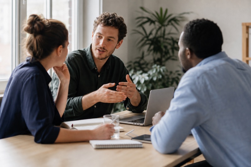 Three colleagues reviewing campaign creative around a table.